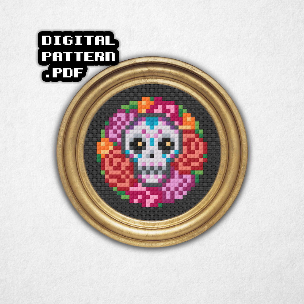 Digital rendering of a mini cross stitch pattern on black aida cloth in a round gold frame of a traditional style Mexican sugar skull with purple turquoise and pink highlights sitting on colorful roses in the background! Digital pattern PDF is on the top left.